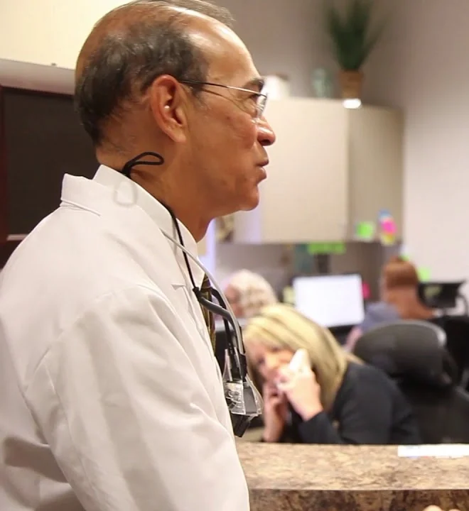 Dr. Cedric Chenet at the front desk of his practice, with the front desk team behind him.