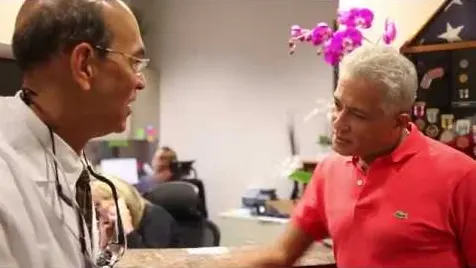 Dr. Chenet laughing with a patient at the front desk of the practice.